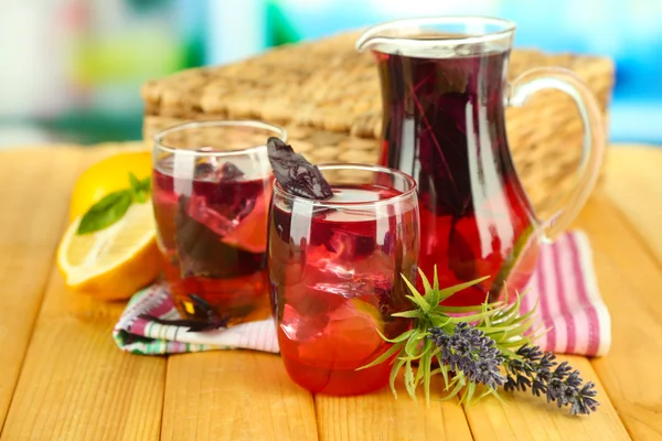 Red basil lemonade in jug and glass, on wooden table, on bright background — Stock Photo, Image