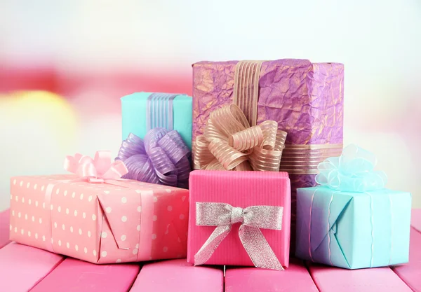 Beautiful bright gifts, on bright wooden table — Stock Photo, Image