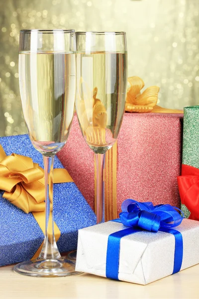 Glazen champagne met geschenkdozen op glanzende achtergrond — Stockfoto