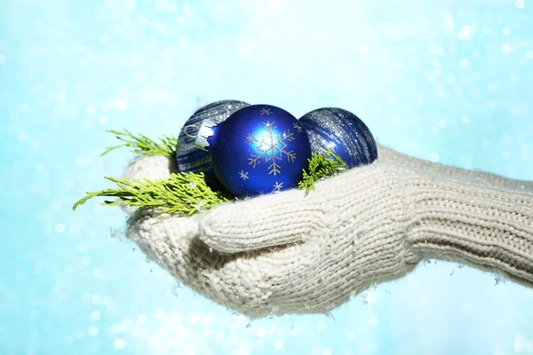 Female hands in mittens Christmas tree balls, on color background — Stock Photo, Image