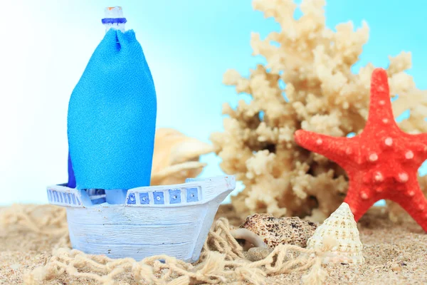 Statek zabawka niebieski na piasku, na niebieskim tle — Zdjęcie stockowe