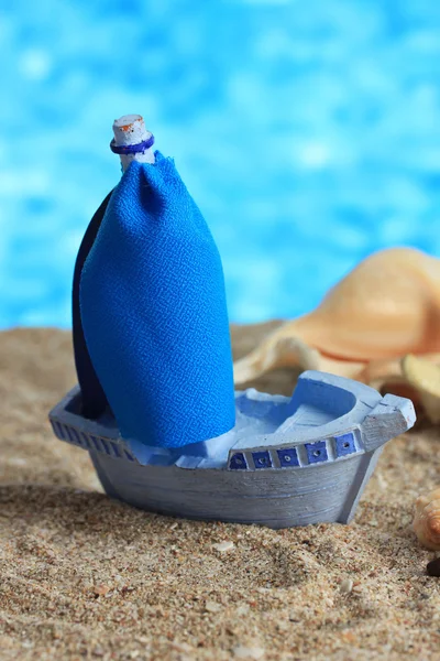 Blue toy ship on sand, on blue background — Stock Photo, Image