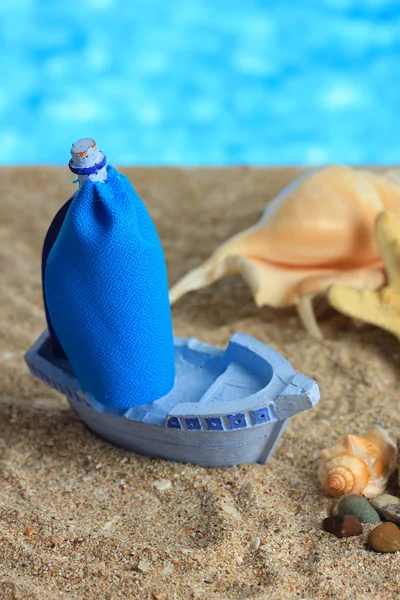 Navio de brinquedo azul na areia, no fundo azul — Fotografia de Stock