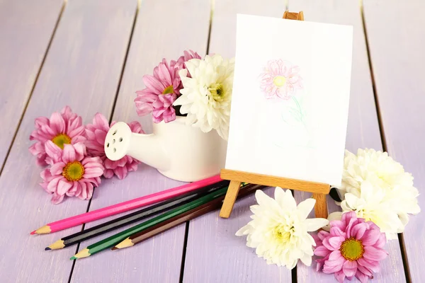 Composición de flores y caballete pequeño con cuadro sobre mesa de madera de primer plano — Foto de Stock