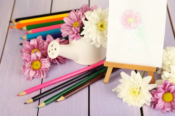 Composición de flores y caballete pequeño con cuadro sobre mesa de madera de primer plano —  Fotos de Stock