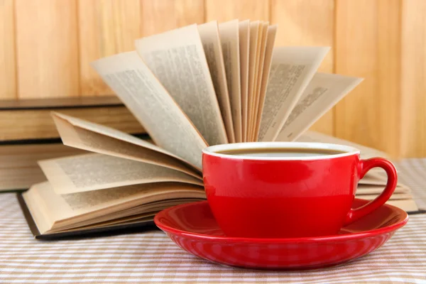 Tazza di caffè e libri su tovaglia su sfondo di legno — Foto Stock