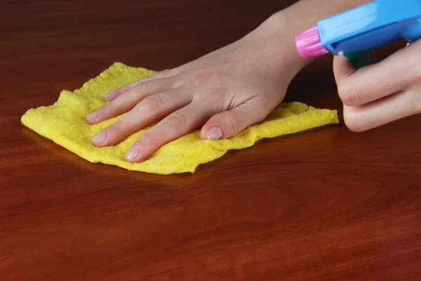 De hand afvegen houten oppervlak met gele doek en spuit — Stockfoto