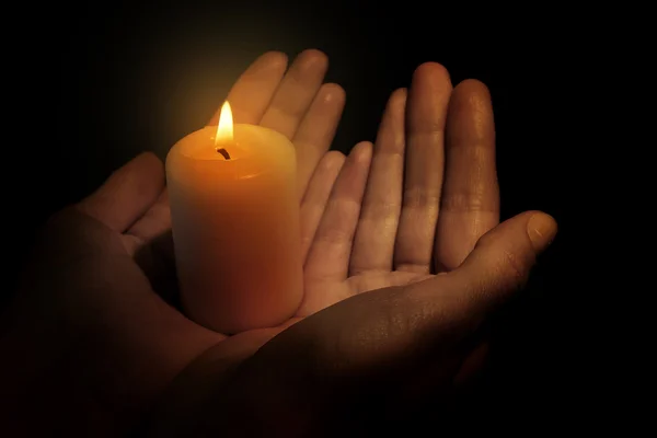 Burning candle in hands isolated on black — Stock Photo, Image