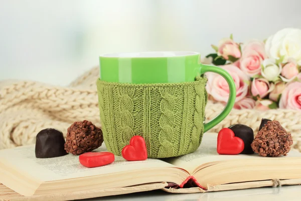 Cup with knitted thing on it and open book close up — Stock Photo, Image