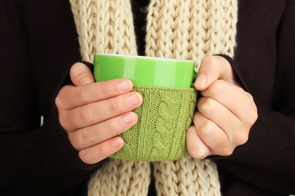 Cup with knitted thing on it in female hands close up — Stock Photo, Image