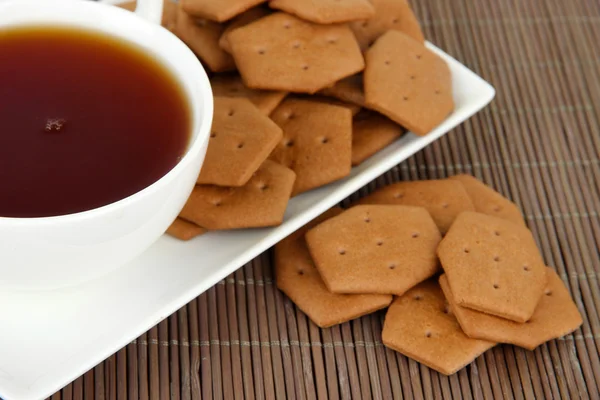 Schokoladenknacker mit Tasse Tee auf Bambus-Hintergrund — Stockfoto