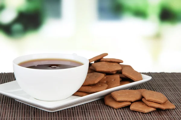 Cracker al cioccolato con tazza di tè su tappetino di bambù su sfondo luminoso — Foto Stock