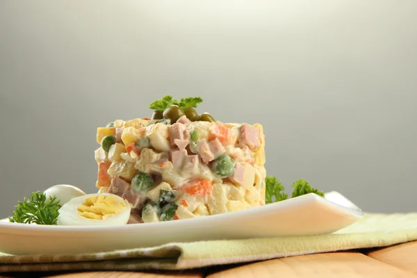 Salada tradicional russa Olivier, em guardanapo de cor, em mesa de madeira, em fundo cinza — Fotografia de Stock