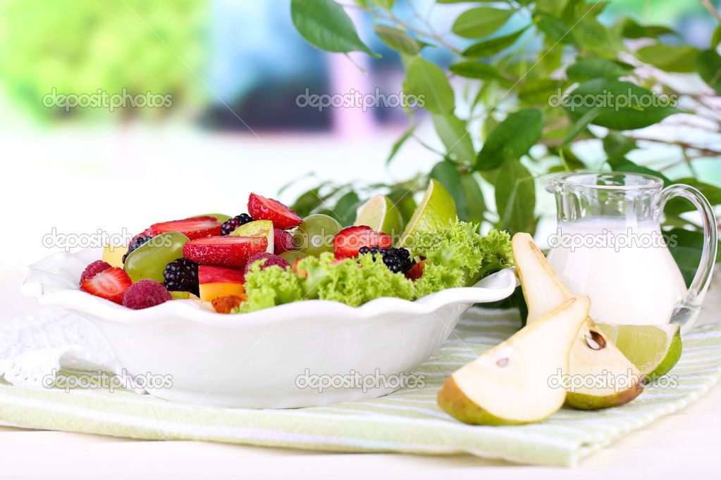 Fruit salad in plate on napkin wooden table on nature background