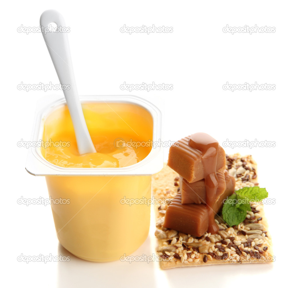 Tasty yogurt in open plastic cup, cookies and toffee candies isolated on white