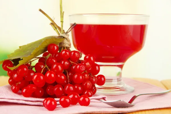 Красные ягоды вибурнума и чаши с вареньем на столе на ярком фоне — стоковое фото