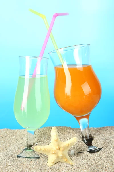 Beach cocktails in sand on blue background — Stock Photo, Image