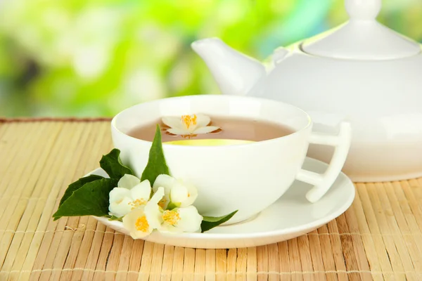 Kopje thee met jasmijn, op bamboe mat, op lichte achtergrond — Stockfoto