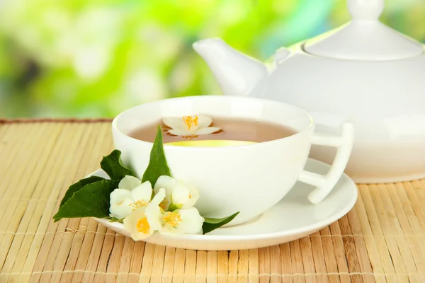 Cup of tea with jasmine, on bamboo mat, on bright background — Stock Photo, Image