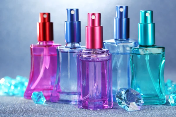 Perfume de las mujeres en hermosas botellas sobre fondo brillante —  Fotos de Stock