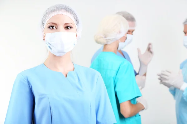 Chirurgen stehen auf grauem Hintergrund — Stockfoto