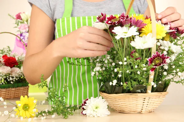 Floristería hace ramo de flores en canasta de mimbre — Foto de Stock