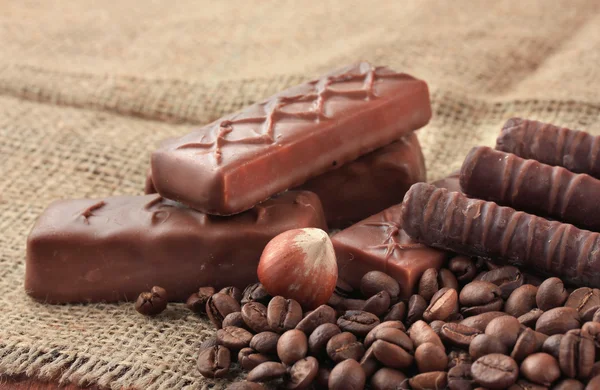 Heerlijke chocolade repen met noten en koffiebonen op rouwgewaad achtergrond — Stockfoto