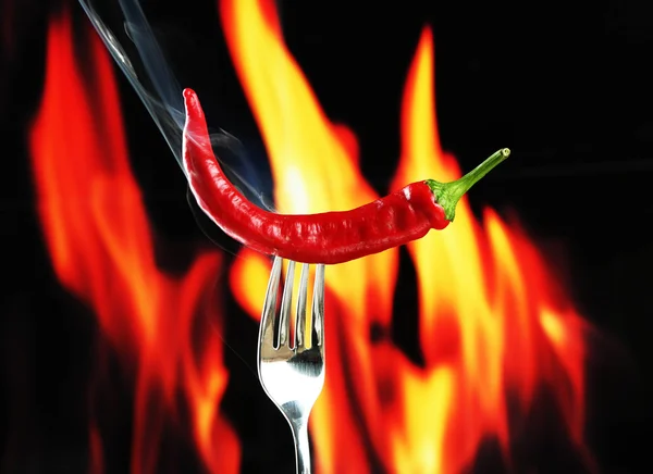 Peperoncino piccante rosso sulla forchetta, sullo sfondo del fuoco — Foto Stock