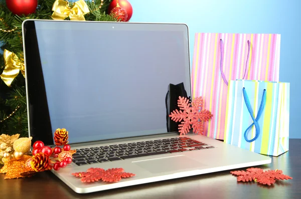 Laptop mit Geschenken auf Tisch auf blauem Hintergrund — Stockfoto