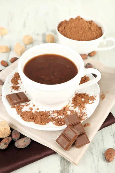 Kakaový prášek v poháru na ubrousek na dřevěný stůl — Stock fotografie