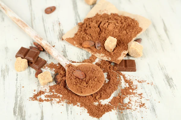 Cocoa powder in spoon on wooden table — Stock Photo, Image