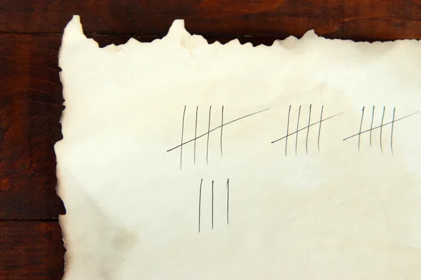 Counting days by drawing sticks on paper on wooden background — Stock Photo, Image