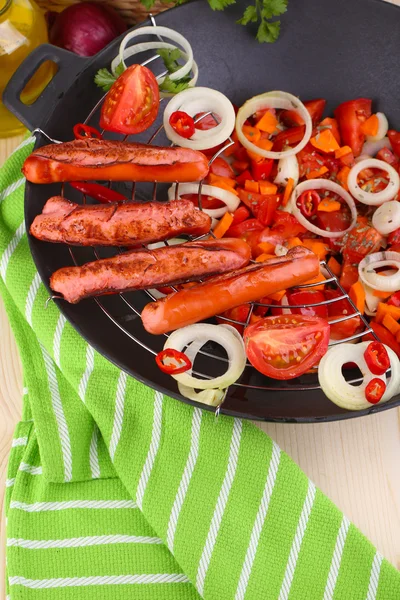 Delicious sausages with vegetables in wok on wooden table close-up — Stock Photo, Image