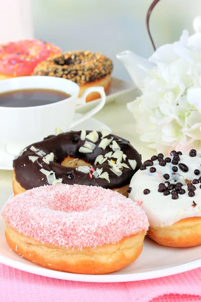 Doce donuts com xícara de chá na mesa em fundo claro — Fotografia de Stock