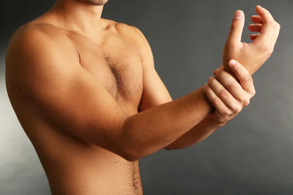 Young man with hand pain on grey background — Stock Photo, Image