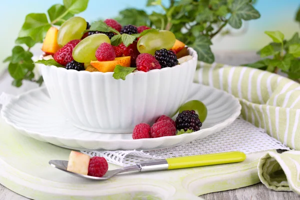 Salade de fruits dans un bol, sur une table en bois, sur un fond lumineux — Photo