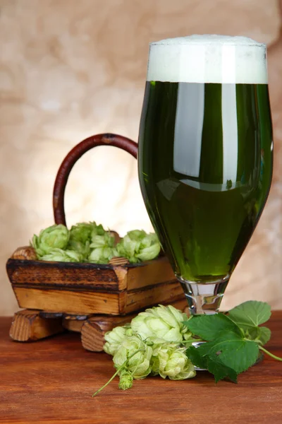 Glas mit grünem Bier und Hopfen, auf Holztisch — Stockfoto