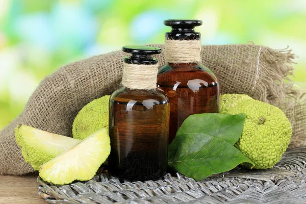 Osage Orange fruits (Maclura pomifera) and medicine bottles, on wooden table, on nature background — Stock Photo, Image