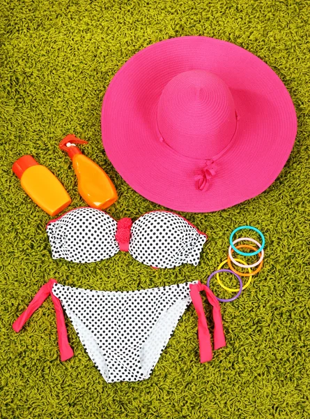 Swimsuit and beach items on green background — Stock Photo, Image