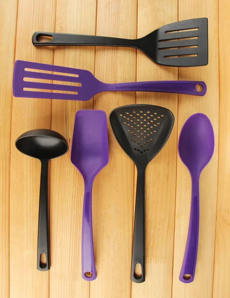 Plastic kitchen utensils on wooden background — Stock Photo, Image