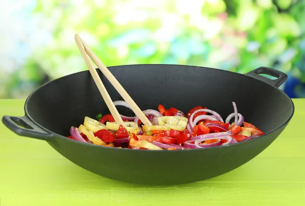 Verdure in wok su tavolo di legno su sfondo naturale — Foto Stock