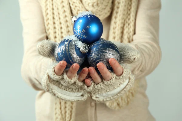 여성 손 장갑에 색 배경 크리스마스 트리 볼 — 스톡 사진