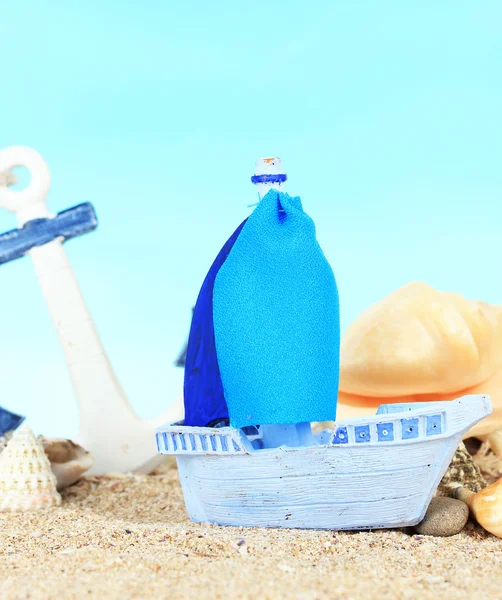 Blue toy ship on sand, on blue background — Stock Photo, Image