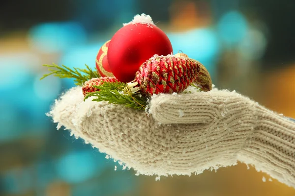 Manos femeninas en manoplas Bolas de árbol de Navidad, sobre fondo de color —  Fotos de Stock