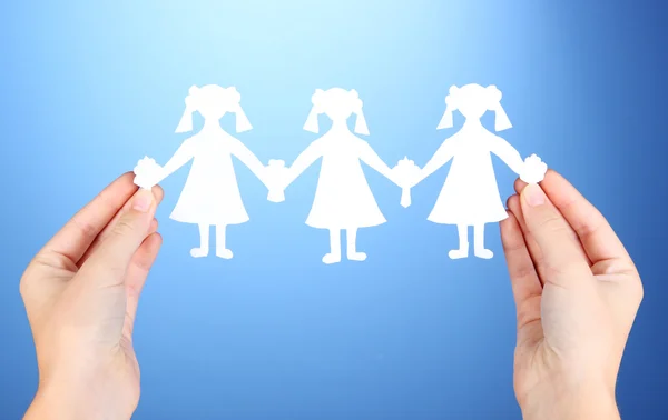 Paper people in hands on blue background — Stock Photo, Image