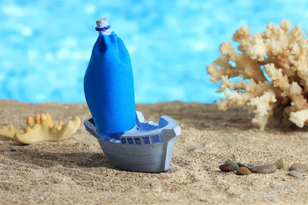 Blaues Spielzeugschiff auf Sand, auf blauem Hintergrund — Stockfoto