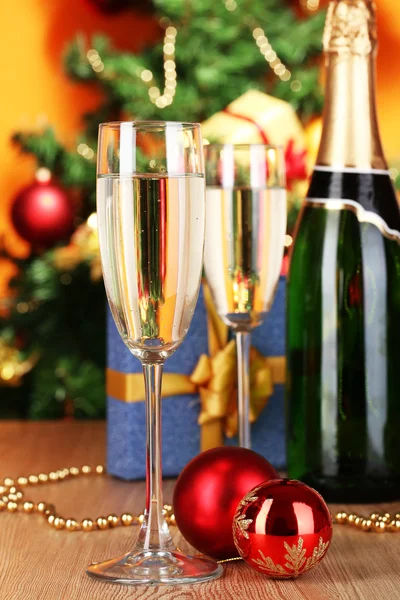 Garrafa de champanhe com copos e bolas de Natal na mesa de madeira no fundo da árvore de Natal — Fotografia de Stock