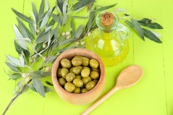 Olive oil branch and olive in bowl on wooden table — Stock Photo, Image