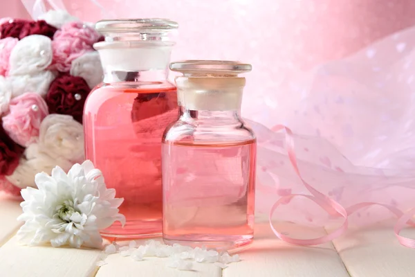 Bouteilles en verre avec essence de couleur, sur fond rose — Photo