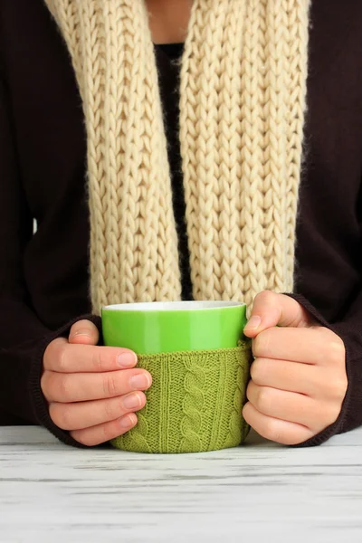 Cup met gebreide ding op het in vrouwelijke handen close-up — Stockfoto